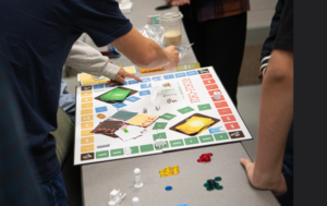 Figure 2: Composite photographs of the students playing their games in class. One game was a boardgame with 3-d printed tokens printed by the students and the other was more of a card game with tokens. 